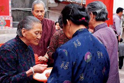 黄福娣把祭神的米派给村民，祈愿神明保佑